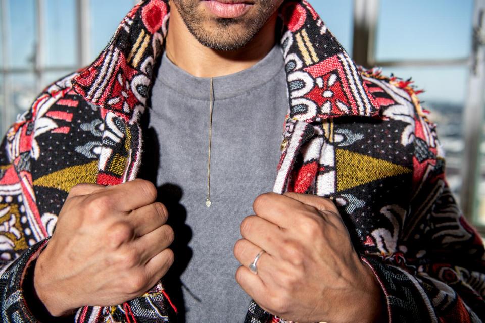 A close-up shot of a man opening his geometric jacket.