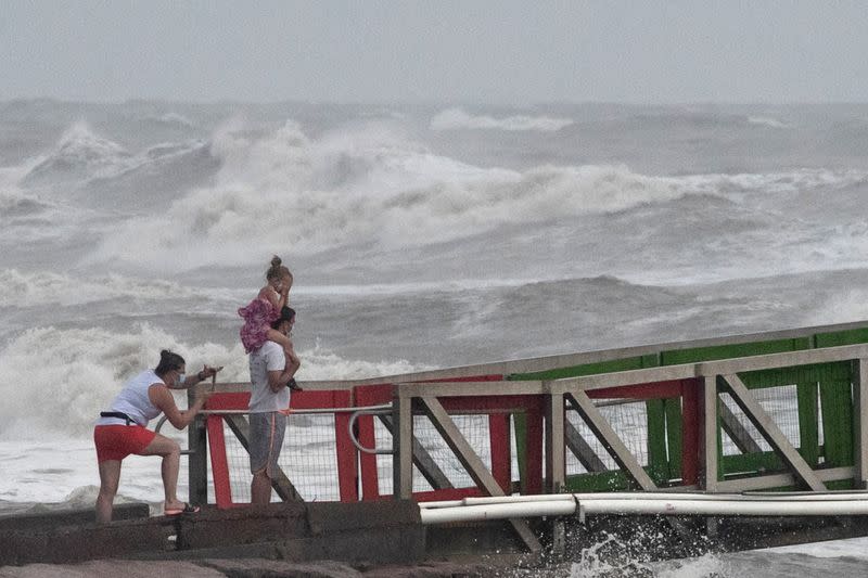 A family watches high swells from Hurricane Hanna from a jetty in Galveston, Texas