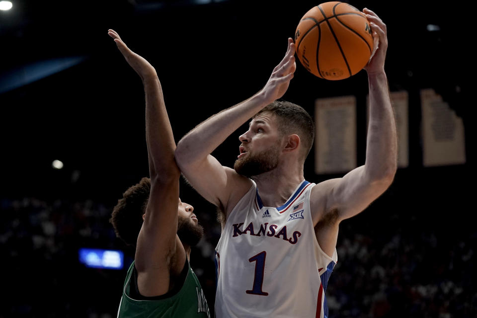 Kansas center Hunter Dickinson (1) looks to shoot over Manhattan forward Daniel Rouzan during the first half of an NCAA college basketball game Friday, Nov. 10, 2023, in Lawrence, Kan. (AP Photo/Charlie Riedel)