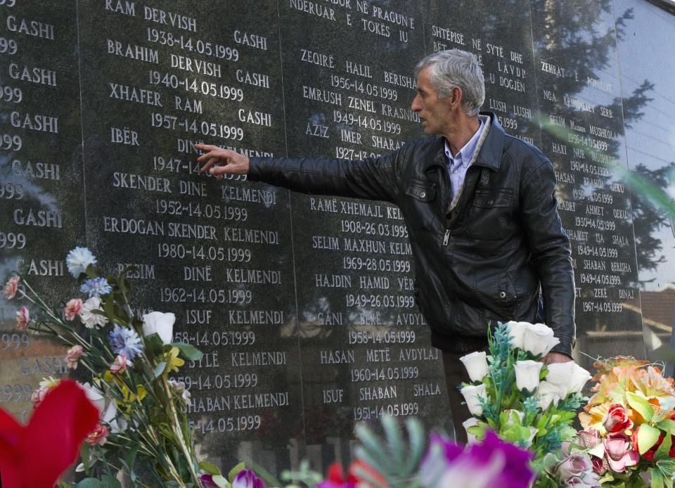 Rexhe Kelmendi, one of three survivors of the Cuska massacre, points out the names of family members as he visits the Martyr's cemetery in the village of Cuska, Kosovo on Tuesday, Feb. 11, 2014. Serbia's war crimes court on Tuesday convicted nine former paramilitaries of the brutal killings of more than 100 ethnic Albanian civilians during the Kosovo war and sentenced them to between two and 20 years in prison. The crime by the "Jackals" paramilitary group includes the massacre of 41 people in the Kosovo village of Cuska where Serbs rounded up villagers, robbed them, separated women and children from men, locked the men in a house and set it on fire. The brutality of Serbia's crackdown prompted NATO to intervene with airstrikes to stop the war. (AP Photo/Visar Kryeziu)