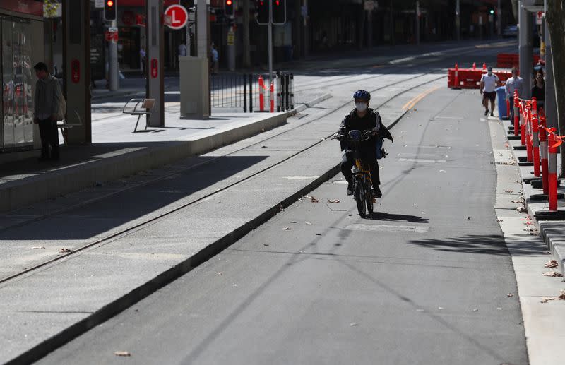 A man rides a scooter by an almost empty street during a workday following the implementation of stricter social-distancing and self-isolation rules to limit the spread of the coronavirus disease (COVID-19) in Sydney