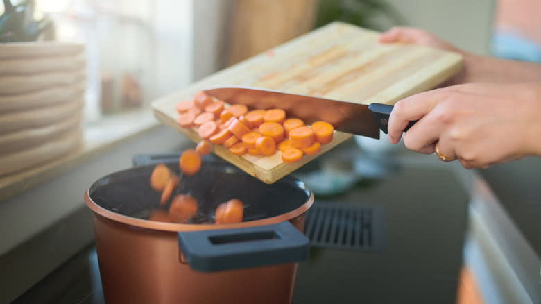 hands adding carrots to a pot