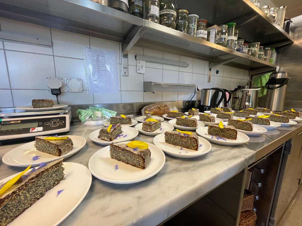 Slices of cake on white plates on a marble surface.