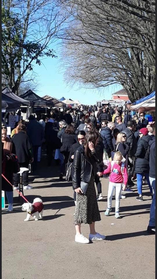 The photo shows a crowd of adults, children and even dogs at a busy small-town market in Victoria.