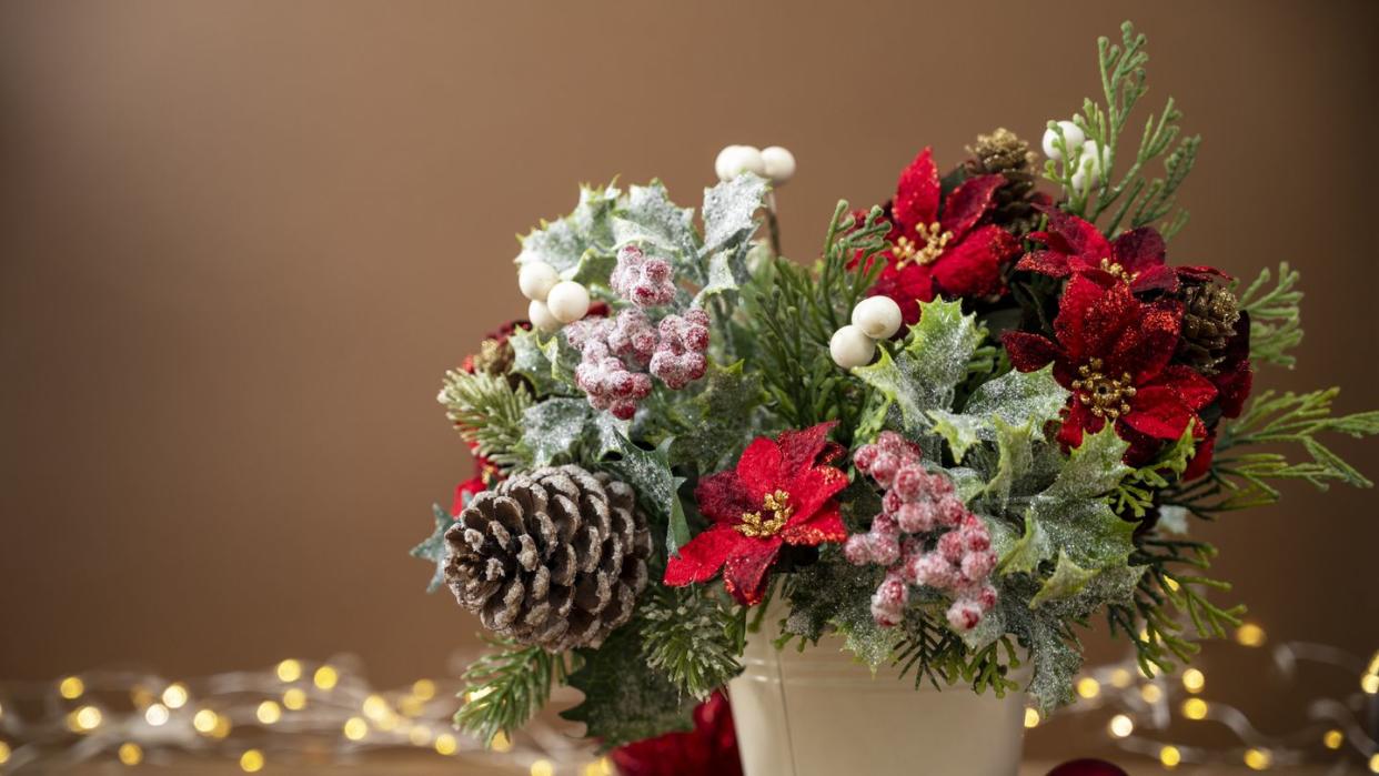 christmas festive arrangement with red poinsettia on brown background with bokeh lights