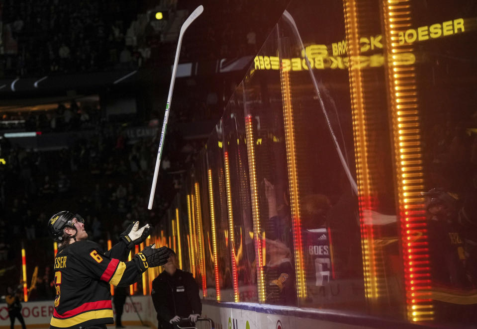 Vancouver Canucks' Brock Boeser, who recorded a hat trick, tosses a stick into the crowd after being named the game's first star after an NHL hockey game against the Tampa Bay Lightning in Vancouver, B.C., on Tuesday, Dec. 12, 2023. (Darryl Dyck/The Canadian Press via AP)