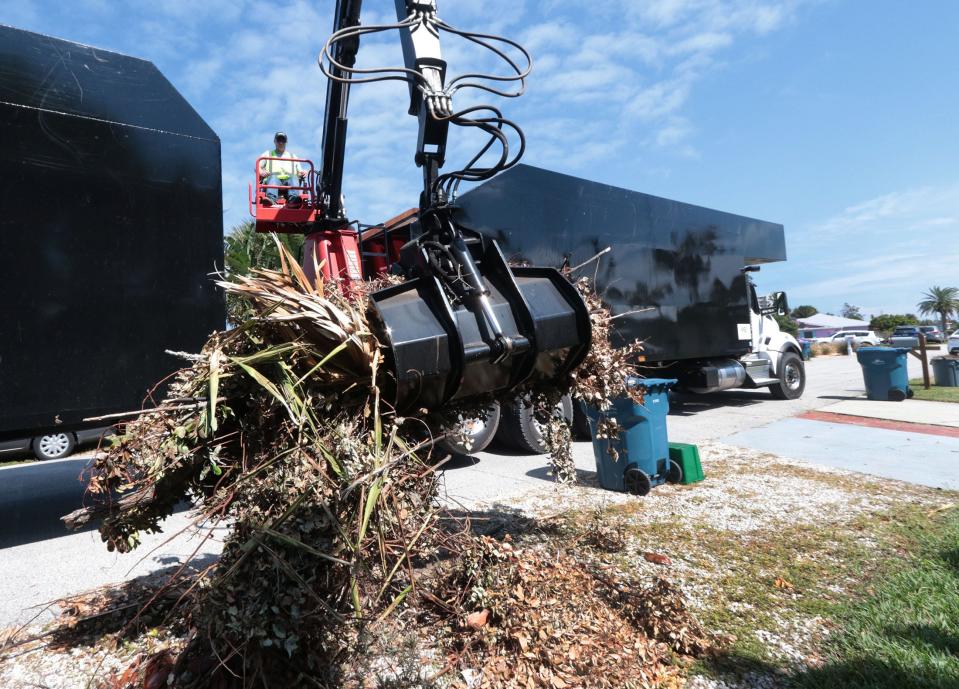 Zach Burke grabs another bundle of hurricane debris Monday, October 10, 2022, on River Drive in Ormond Beach as he loads a trailer, one of many working in the county.