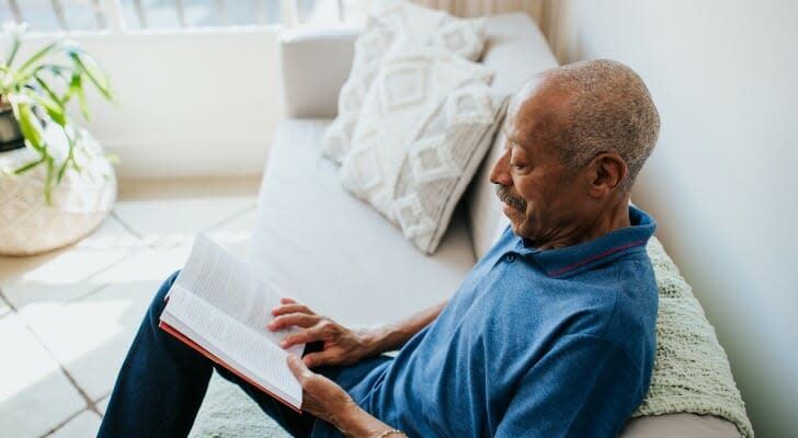 A man reads a book about planning for retirement.  SmartAsset has put together a roundup of the best retirement planning books to read in 2022. 