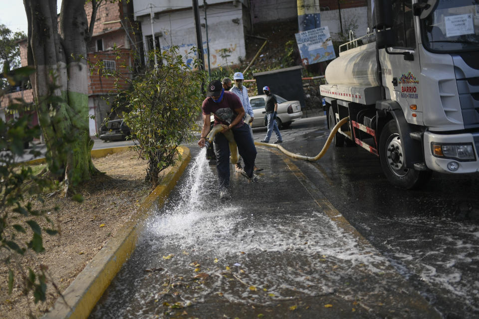 Volunteers clean a pedestrian walkway during a cleaning and disinfection day organized by the communal council and pro-government groups known as "Colectivos" at the 23 de Enero neighborhood of Caracas, Venezuela, Wednesday, April 29, 2020, during a government-imposed quarantine to help stop the spread of the new coronavirus. (AP Photo/Matias Delacroix)