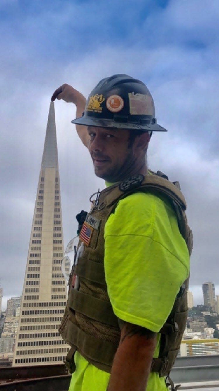 Joshua Shepperd stands on One Maritime Plaza, a skyscraper in San Francisco, while positioned in front of the Transamerica Pyramid. Shepperd works as a glazier, and had previously served in the United States Army.