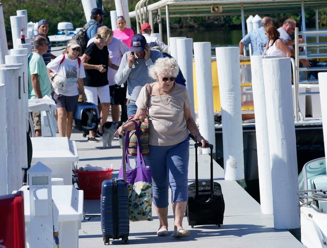 Maryann Loh walks down the dock after being rescued from Sanibel Island after Hurricane Ian passed by the area Saturday, Oct. 1, 2022, in Fort Myers, Fla. (AP Photo/Steve Helber)