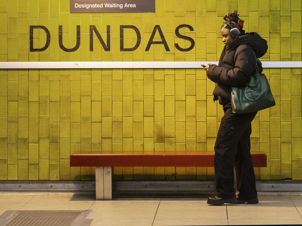  A woman uses her phone while waiting for the TTC subway at Dundas Street and Yonge Street in Toronto.