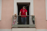 Un hombre se asoma al exterior desde el balcón de su casa de Barcelona junto a sus dos hijos pequeños. (Foto: David Zorrakino / Europa Press / Getty Images).