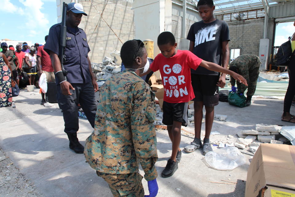 A marine searches a boy as he joins others who will be evacuated by ship to Nassau in the aftermath of Hurricane Dorian, at the Marsh Harbor port, Great Abaco, Bahamas, Friday, Sept. 6, 2019. Bahamian officials on the scene said that searches were a standard precautionary measure to check for dangerous items or unhealthy substances. (AP Photo/Gonzalo Gaudenzi)