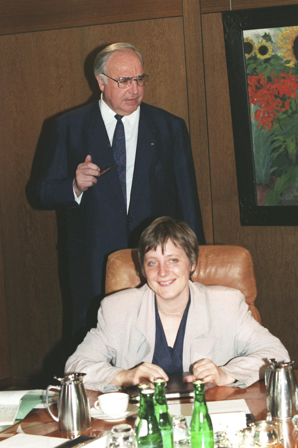 FILE - In this Tuesday, April 30, 1991 file photo, German Chancellor Helmut Kohl, stands behind Women and Youth Minister Angela Merkel prior to a cabinet meeting in the Chancellory in Bonn Germany. German journalists' comments on Merkel's appearance were often openly sexist, particularly in the beginning of her career. German media first dubbed her “Kohl's girl,” because Merkel was initially promoted by then-Chancellor Helmut Kohl, and later called her “Mutti,” or “mommy,” even though Merkel has no children. (AP Photo/Fritz Reiss, File)