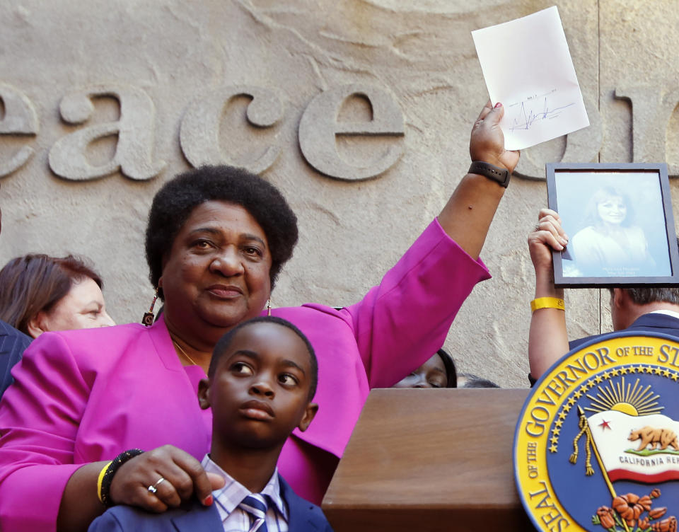 Assemblywoman Shirley Weber, D-San Diego, holds up her measure signed by Gov. Gavin Newsom that limits the use of lethal force by law enforcement Sacramento, Calif., Monday, Aug. 19, 2019. Weber's bill, AB392, would bar police from using lethal force unless it is necessary to prevent imminent threat of death or serious injury to themselves and others. (AP Photo/Rich Pedroncelli)