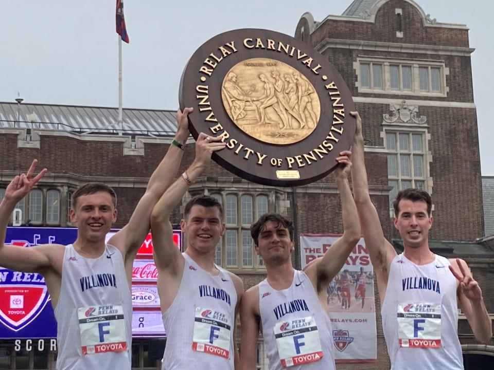 Millstone's Liam Murphy (second from right) holds up the Penn Relays winner's wheel after anchoring Villanova to victory in the men's 4xmile.