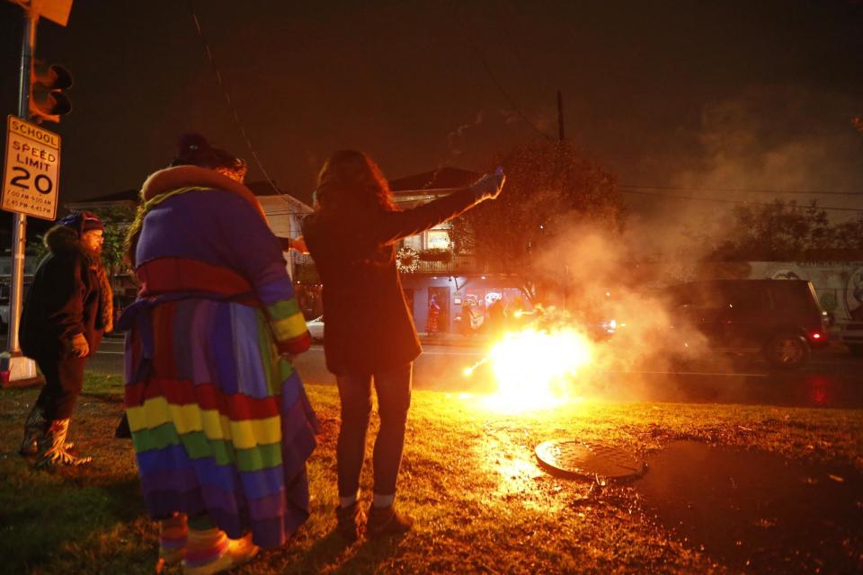 Revelers of the "Societe des Champs Elysee" launch fireworks before boarding the Rampart-St. Claude street car line, which just opened last fall, to commemorate the official start of Mardi Gras season, in New Orleans, Friday, Jan. 6, 2017. Wearing masks and festive costumes, they honored their king and queen at a neighborhood bar and danced as a brass band played "Carnival Time," before boarding their red street car. (AP Photo/Gerald Herbert)