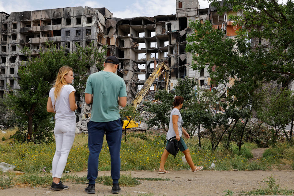 Local residents stand in front of a destroyed apartment building, that is being demolished, in the course of Ukraine-Russia conflict in the southern port city of Mariupol, Ukraine August 21, 2022. REUTERS/Alexander Ermochenko