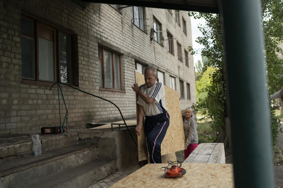 Henadii Sydorenko carries a piece of plywood to cover the windows of apartments that have been damaged after a Russian attack yesterday near a residential area in Sloviansk, Ukraine, Monday, Sept. 5, 2022. (AP Photo/Leo Correa)