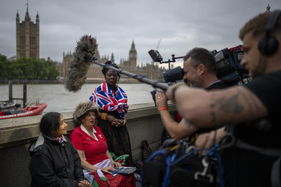 FILE - Vanessa, Anne and Grace, from left to right, are interviewed by TV reporters as they wait opposite the Palace of Westminster to be first in line bidding farewell to Queen Elizabeth II in London, Tuesday, Sept. 13, 2022. Plans by news organizations that have been in place for years — even decades — to cover the death of Queen Elizabeth II were triggered and tested when the event took place. London has been inundated with journalists, with more headed to the city for the funeral services on Monday. (AP Photo/Emilio Morenatti, File)