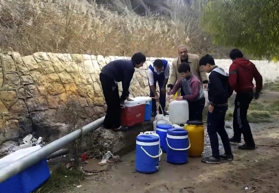 This frame grab from video provided By Yomyat Kzefeh Hawen Fi Dimashq (Diary of a Mortar Shell in Damascus), a Damascus-based media outlet that is consistent with independent AP reporting, shows Syrian residents filling up buckets and gallons of spring water from a pipe on the side of the road, in Damascus, Syria. Water supplies to Damascus have been largely cut off for nearly two weeks because of fighting between pro-government forces and rebels for control of the main tributary, forcing millions in the Syrian capital to scramble for enough to drink and wash with. The cut-off is a major challenge to the government’s effort throughout the nearly 6-year-old civil war to keep the capital as insulated as possible from the effects of the conflict tearing apart much of the country. (Yomyat Kzefeh Hawen Fi Dimashq (Diary of a Mortar Shell in Damascus), via AP)