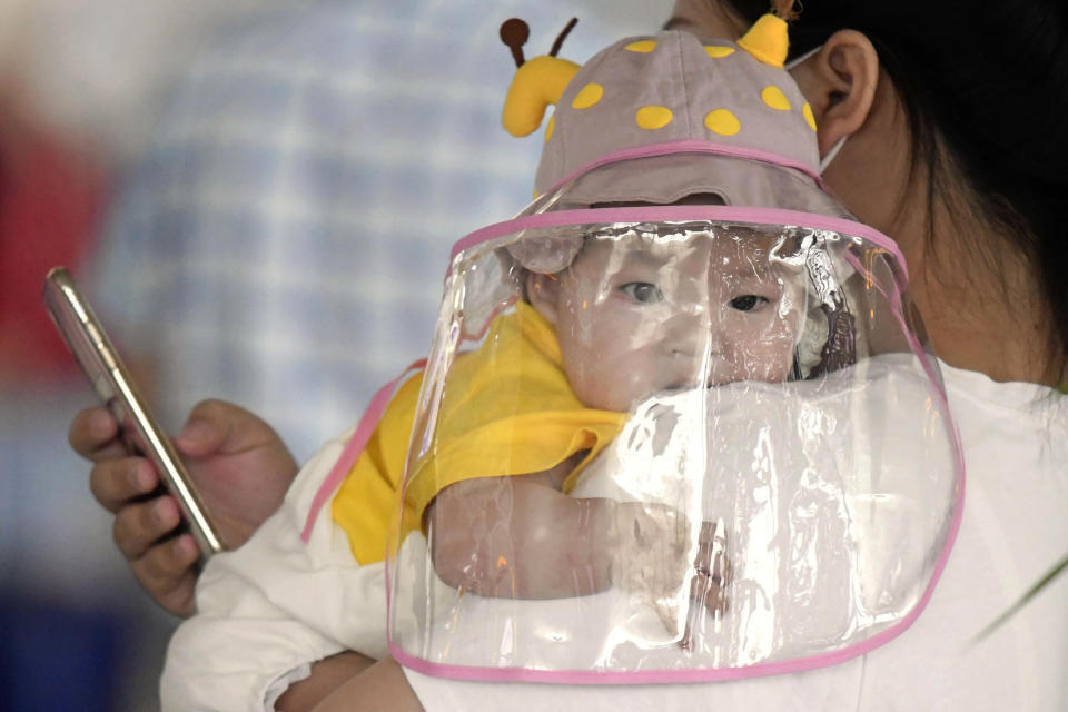 Un bebé con una pantalla facial espera para embarcar en un avión en Wuhan, en el centro de China, en la provincia de Hubei, el 23 de mayo de 2020. (Kyodo News via AP)