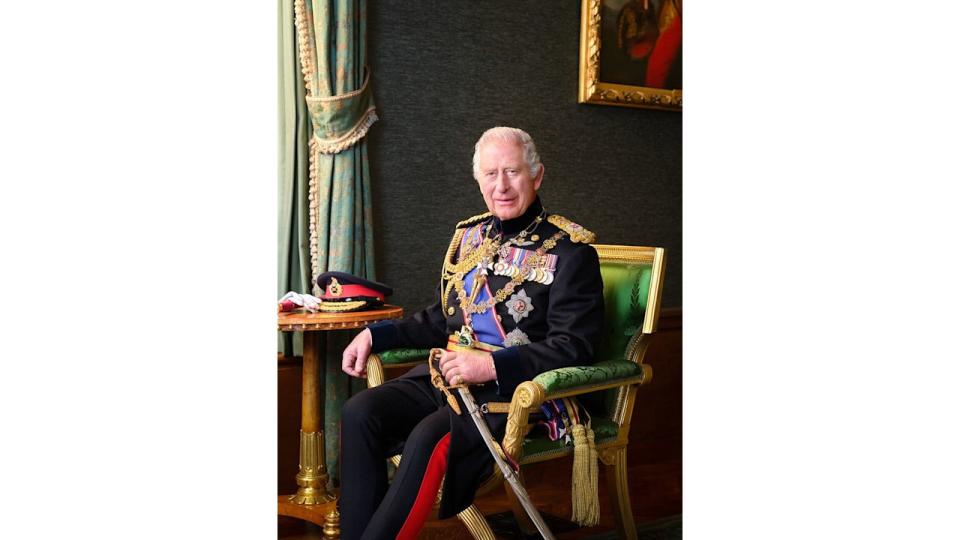 King Charles in a black military uniform sati n a green chair