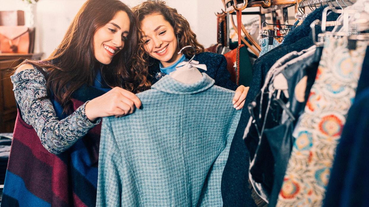 Two friends shopping for clothes in a store.