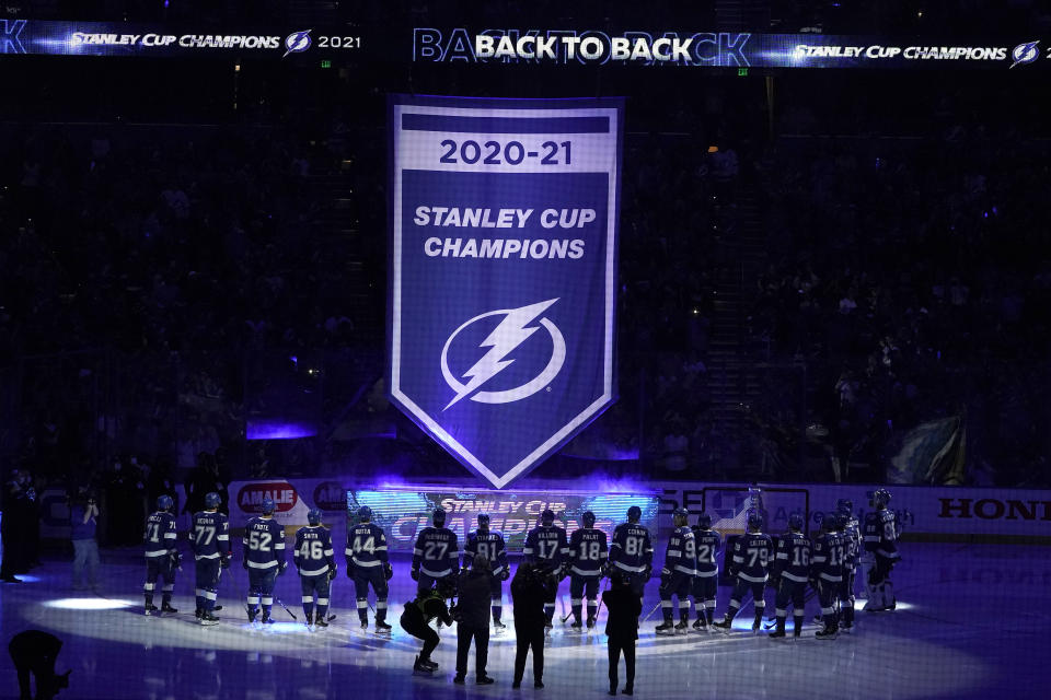 Tampa Bay Lightning players watch as their 2021 Stanley Cup Champions banner is raised before an NHL hockey game against the Pittsburgh Penguins Tuesday, Oct. 12, 2021, in Tampa, Fla. (AP Photo/Chris O'Meara)