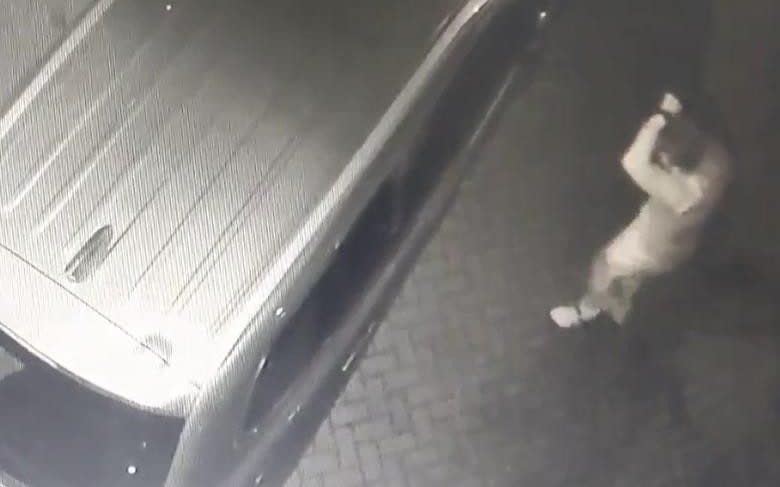 One of the thieves breaks into a car