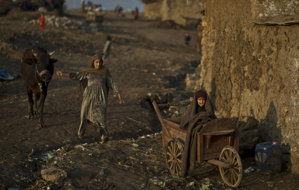 Pakistani child, Saddam Patang, 2, cries while sitting on a wooden cart as he awaits his father outside their home on the outskirts of Islamabad, Pakistan, Friday, Feb. 7, 2014. Saddam's father, mother and his grandparents fled their home from Pakistan's tribal region of Mohmand Agency eight year ago due to fighting between the Taliban and the army and took refuge in Islamabad. (AP Photo/Muhammed Muheisen)