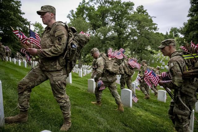 Members of the 3rd U.S. Infantry Regiment also known as The Old Guard place flags in front of each headstone for "Flags-In" at Arlington National Cemetery in Arlington, Thursday, May 25, 2023, to honor the Nation's fallen military heroes ahead of Memorial Day. (AP Photo/Andrew Harnik)