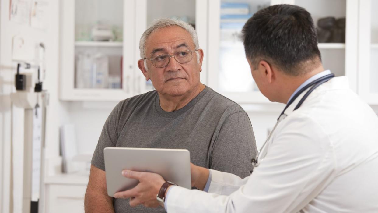 doctor using digital tablet to talk to senior man