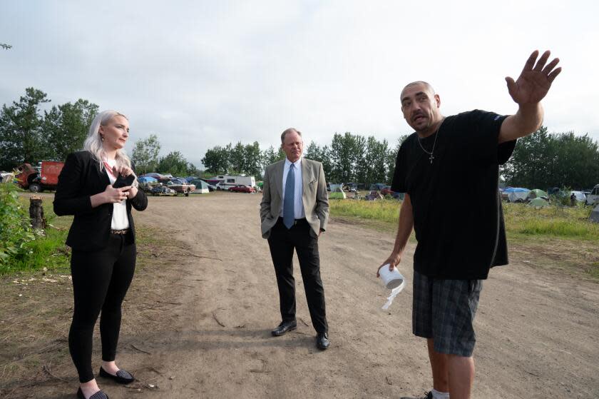 Anchorage Mayor Dave Bronson, center, listen to Ingra homeless camp resident "Joel"