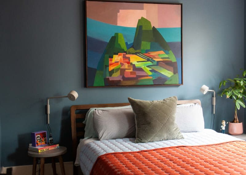 Large painting above neatly made bed.