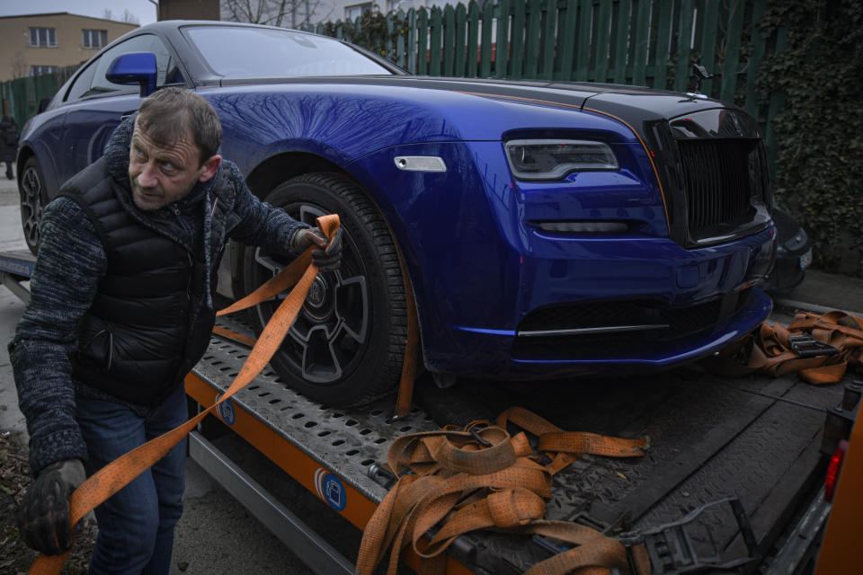 A man secures a luxury vehicle which was seized in a case against media influencer Andrew Tate, is towed away, on the outskirts of Bucharest, Romania, Saturday, Jan. 14, 2023. Prosecutors seized several luxury vehicles after Tate lost a second appeal this week at a Bucharest court, where he challenged the seizure of assets in the late December raids, including properties, land, and a fleet of luxury cars. More than 10 properties and land owned by companies registered to the Tate brothers have also been seized so far. (AP Photo/Alexandru Dobre)