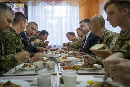 Ukrainian President Petro Poroshenko (3rd R) and NATO Secretary General Jens Stoltenberg (3rd L) share a meal with Ukrainian and Canadian servicemen before inaugurating joint disaster management exercises between Ukraine and NATO countries at the International Center of Peacekeeping and Security in Yavoriv, outside Lviv, Ukraine, in this September 21, 2015 handout photo provided by the Ukrainian Presidential Press Service. REUTERS/Mikhail Palinchak/Ukrainian Presidential Press Service/Handout via Reuters