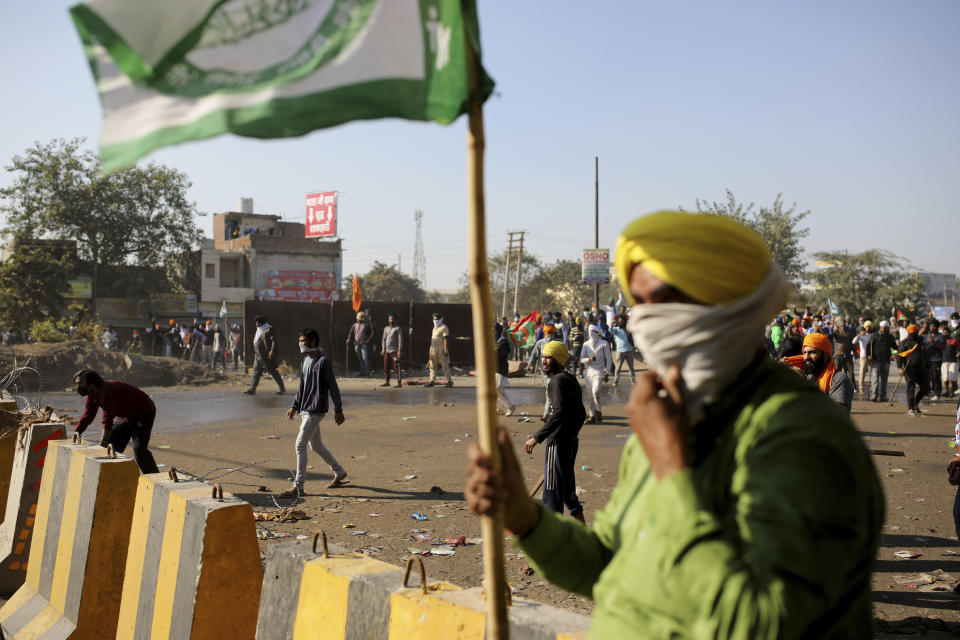 Protesting farmers clash with policemen, as they attempt to move towards Delhi, at the border between Delhi and Haryana state, Friday, Nov. 27, 2020. Thousands of agitating farmers in India faced tear gas and baton charge from police on Friday after they resumed their march to the capital against new farming laws that they fear will give more power to corporations and reduce their earnings. While trying to march towards New Delhi, the farmers, using their tractors, cleared concrete blockades, walls of shipping containers and horizontally parked trucks after police had set them up as barricades and dug trenches on highways to block roads leading to the capital. (AP Photo/Altaf Qadri)