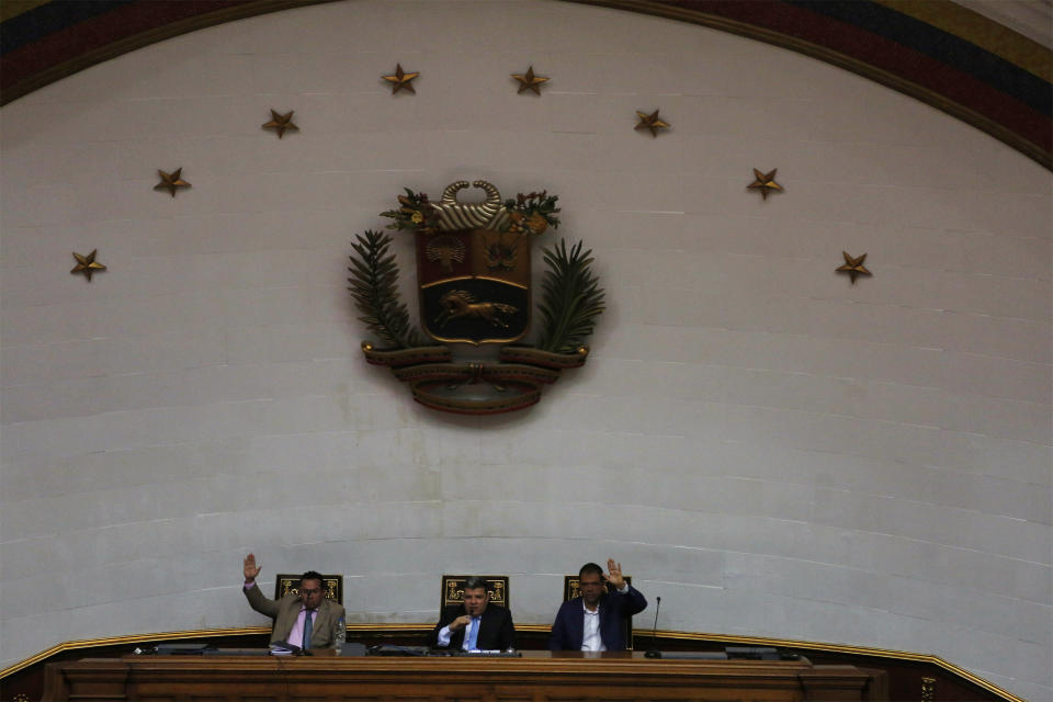 Lawmakers Luis Parra, center, Franklyn Duarte, left, and Jose Noriega, right, vote for the opening of an ordinary session at the National Assembly in Caracas, Venezuela, Tuesday, Jan. 7, 2020. Parra, a former opposition ally, declared himself the National Assembly’s leader on Sunday, then today opposition leader Juan Guaidó and opposition lawmakers pushed their way into the legislative building and swore-in Guaido as president of the legislature. (AP Photo/Andrea Hernandez Briceño)