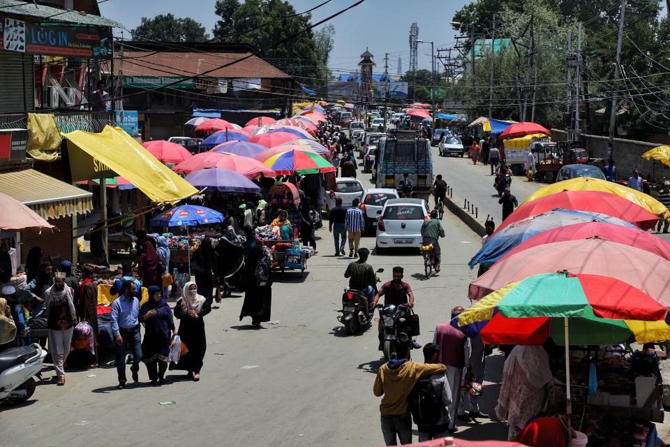 People purchase from a Sunday market as umbrellas are installed on a hot summer day in Sopore District Baramulla Jammu and Kashmir India.
