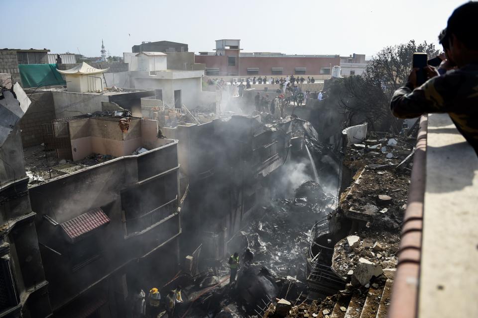 Rescue workers gather at the site after a Pakistan International Airlines aircraft crashed in a residential area in Karachi on May 22, 2020. - A Pakistani passenger plane with nearly 100 people on board crashed into a residential area of the southern city of Karachi on May 22. (Photo by Rizwan TABASSUM / AFP) (Photo by RIZWAN TABASSUM/AFP via Getty Images)