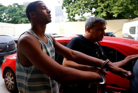 Rai de Souza (L), 22, suspected of being involved in the gang rape of a teenage girl, with a video of the assault circulated widely on social media, is escorted at the Police Station for crimes against minors in Rio de Janeiro, Brazil, May 30, 2016. REUTERS/Ricardo Moraes