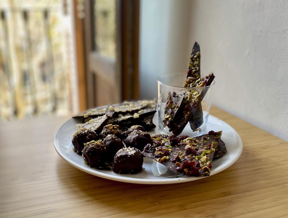 This image shows a plate of chocolate truffles and chocolate bark. Rather than spending on store-bought chocolates for Valentine’s Day, make them together as a fun way to spend the evening with your Valentine. (Albert Stumm via AP)