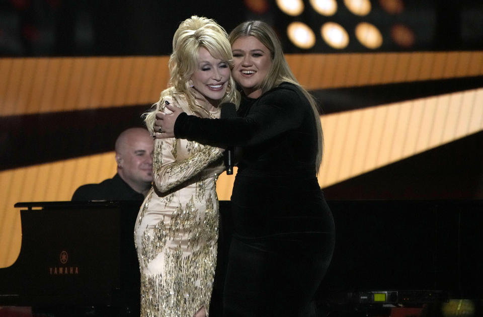 Dolly Parton, a la izquierda, y Kelly Clarkson se abrazan durante la ceremonia de los Premios ACM, el lunes 7 de marzo de 2022 en el Allegiant Stadium en Las Vegas. (Foto AP/John Locher)