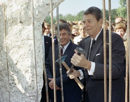 Former U.S. President Ronald Reagan holds a hammer and a chisel next to the Berlin Wall on Poltsdammer Platz in East Berlin in this September 12, 1990 file photo. REUTERS/Stringer