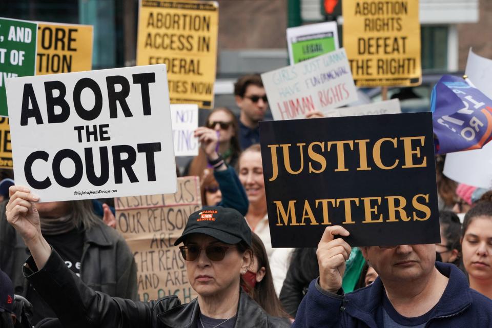 Demonstrators hold signs reading: Abort the Court and Justice Matters.