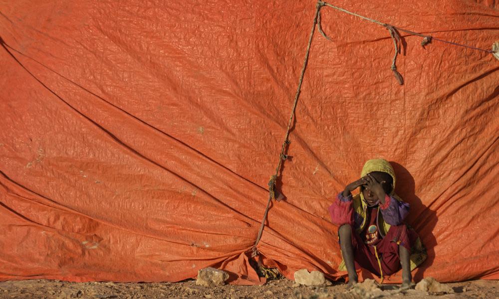 A young Somali boy sits outside his makeshift hut at a camp in Qardho, Somalia, for people displaced from their homes elsewhere in the country by an extended drought.