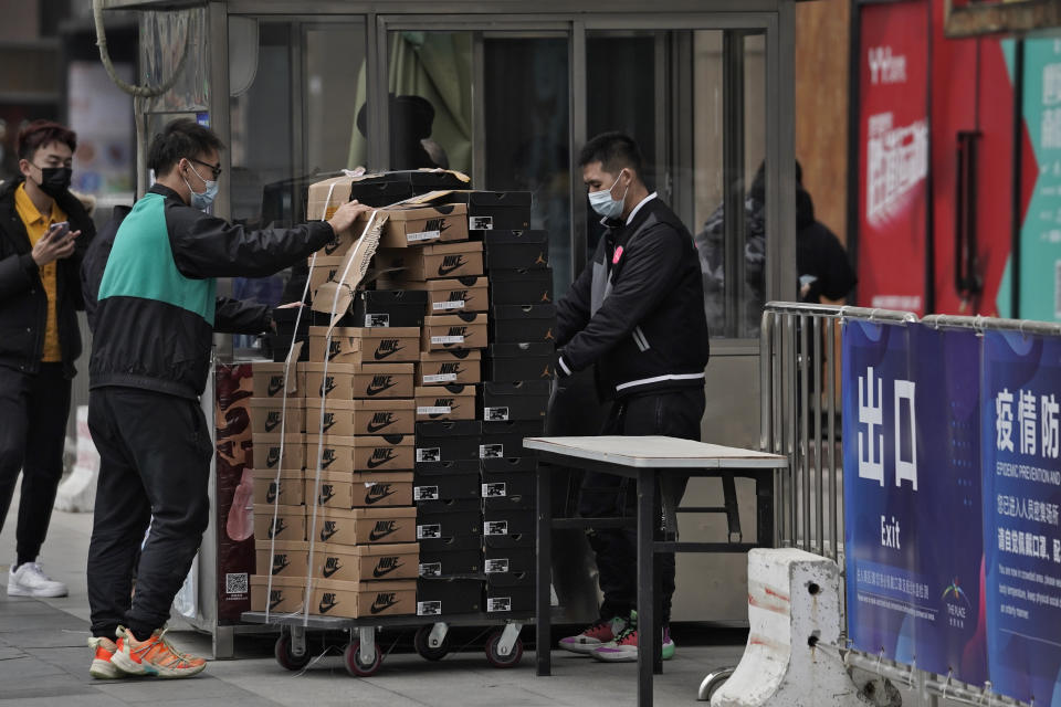 Workers wearing face masks to help curb the spread of the coronavirus push a cart loaded with shoes made by Nike past a security post at a shopping mall in Beijing, Thursday, Jan. 14, 2021. China's exports rose in 2020 despite pressure from the coronavirus pandemic and a tariff war with Washington, boosting its politically volatile trade surplus to $535 billion, one of the highest ever reported. (AP Photo/Andy Wong)