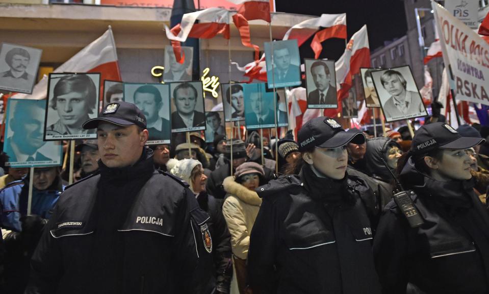 Police officers stand in front of pro-government activists holding portraits of some of the victims of the 1981 martial law and shouting slogans at a passing anti-government march, passing through central Warsaw, on the 35th anniversary of the military crackdown by the country's former communist regime, in Warsaw, Poland, Tuesday, Dec. 13, 2016. (AP Photo/Alik Keplicz)